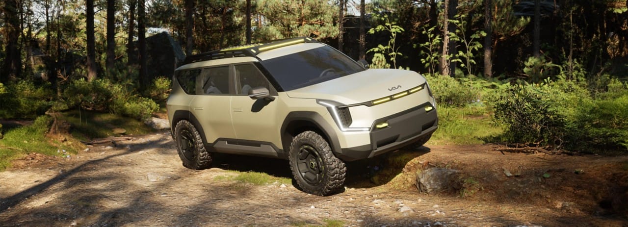 Vehículo de concepto Kia EV9 "ADVNTR" en una vista de tres cuartos, aparcado sobre una gran roca en las montañas.