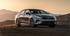  Front passenger-side three-quarter view of a grey Kia sedan parked on mountain terrain.