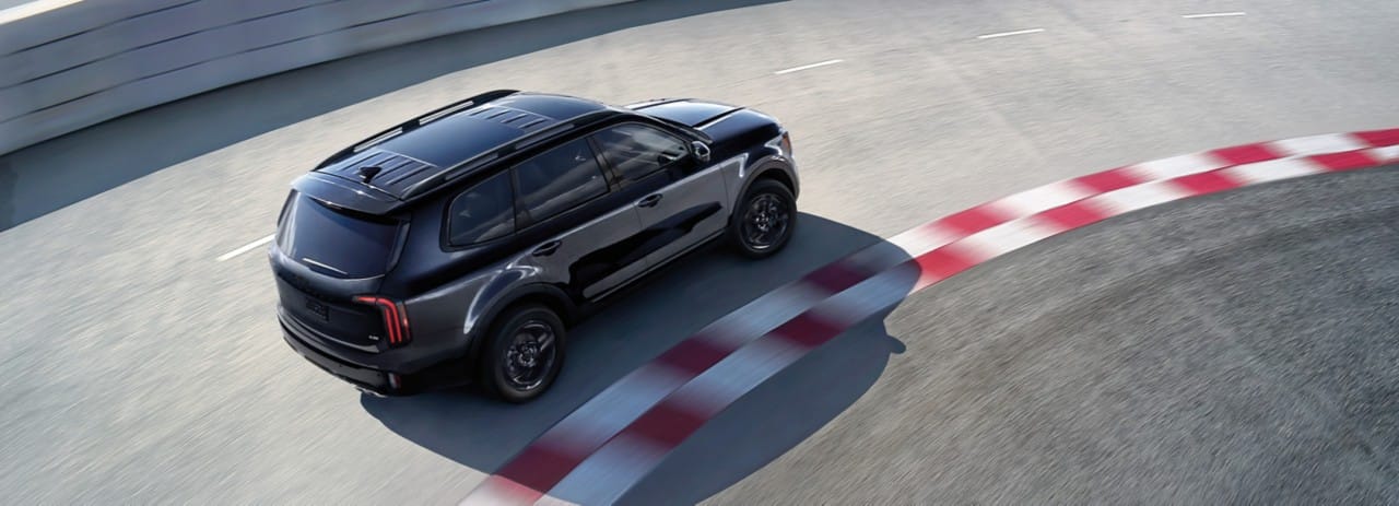 Vehículo Kia negro en una pista con curvas