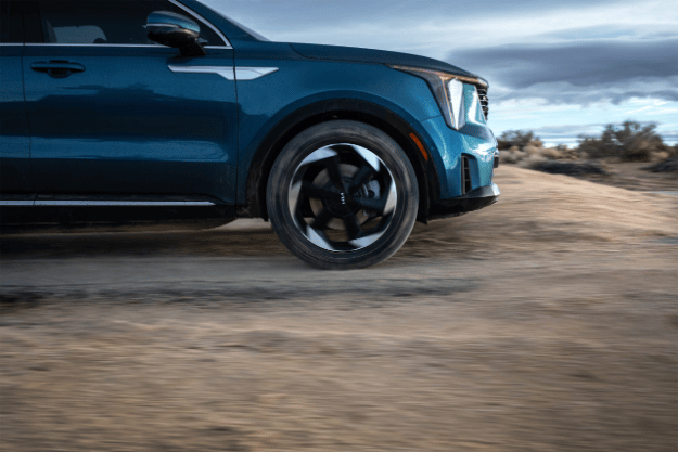 2025 Kia Sorento Hybrid in blue, front view, driving through a puddle of mud in the dessert making a big splash