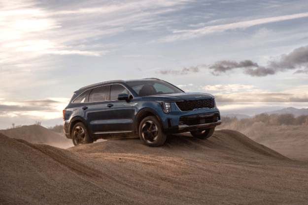 2025 Kia Sorento Hybrid in blue, three-quarter front view, driving over mounds of sand in the desert