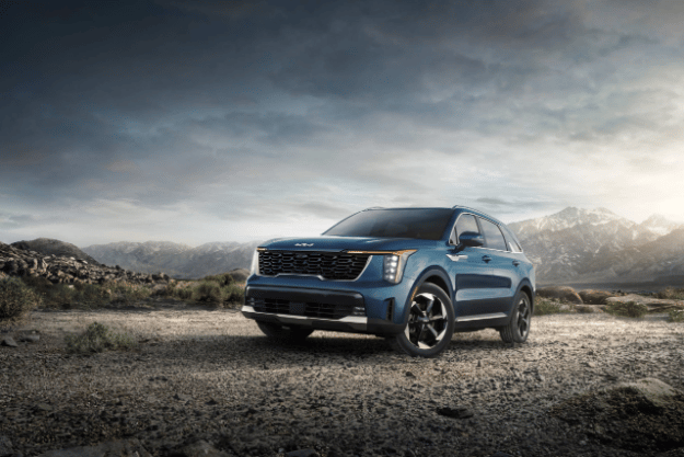 2025 Kia Sorento Hybrid in blue, three-quarter front view, parked in gravel in front of a mountain
