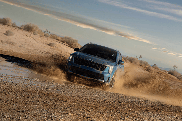 2025 Kia Sorento Hybrid in a three-quarter front view in blue, parked on a desert road