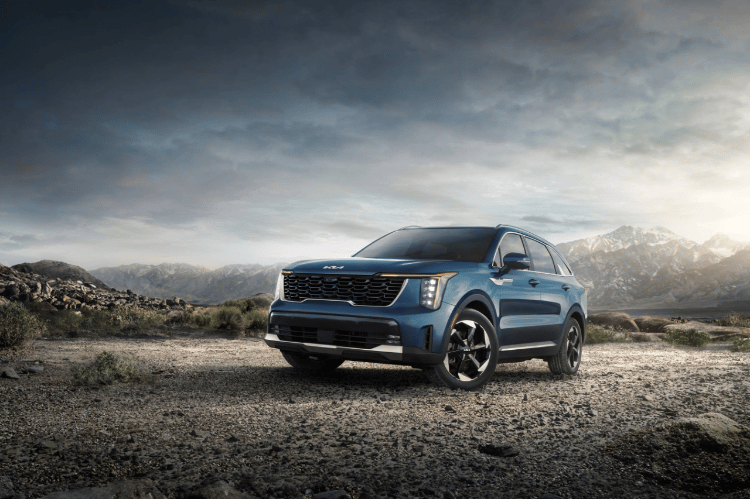 2025 Kia Sorento Hybrid in blue, three-quarter front view, parked in gravel in front of a mountain